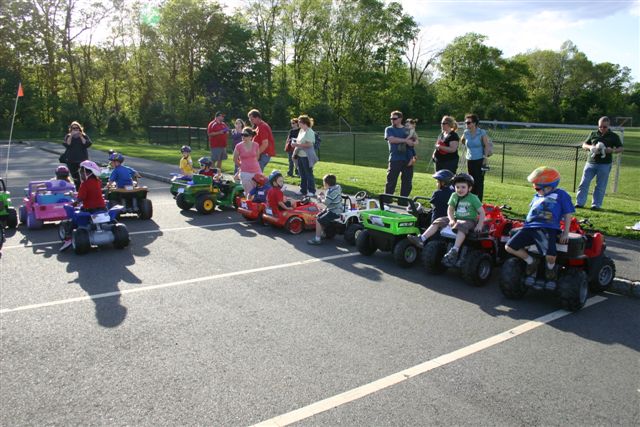 Children in Power Wheels Cars surrounded by parents preparing for their race